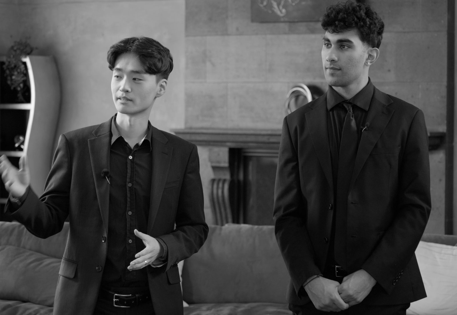 Martin Lee hosting on the set of 10 Humans vs. AI, in black suits in a stone-walled living room